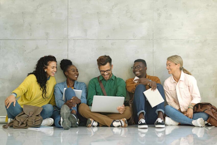 Students in a hallway looking at a laptop